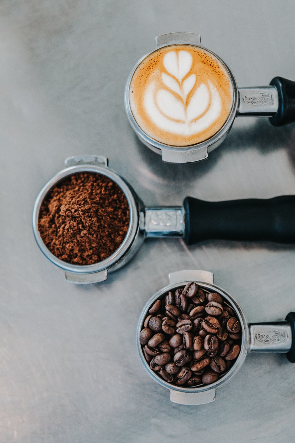 Ylhäältä kuvattu latte art -kahvi, jauhettu kahvi ja kahvipavut